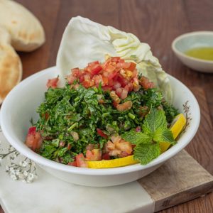 Menu Vibrant tabbouleh salad with fresh ingredients, served with pita bread and lemon wedges.