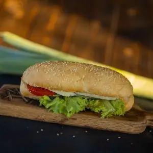 Menú A close-up of a fresh sandwich with lettuce and tomato on a wooden board, ideal for food photography.